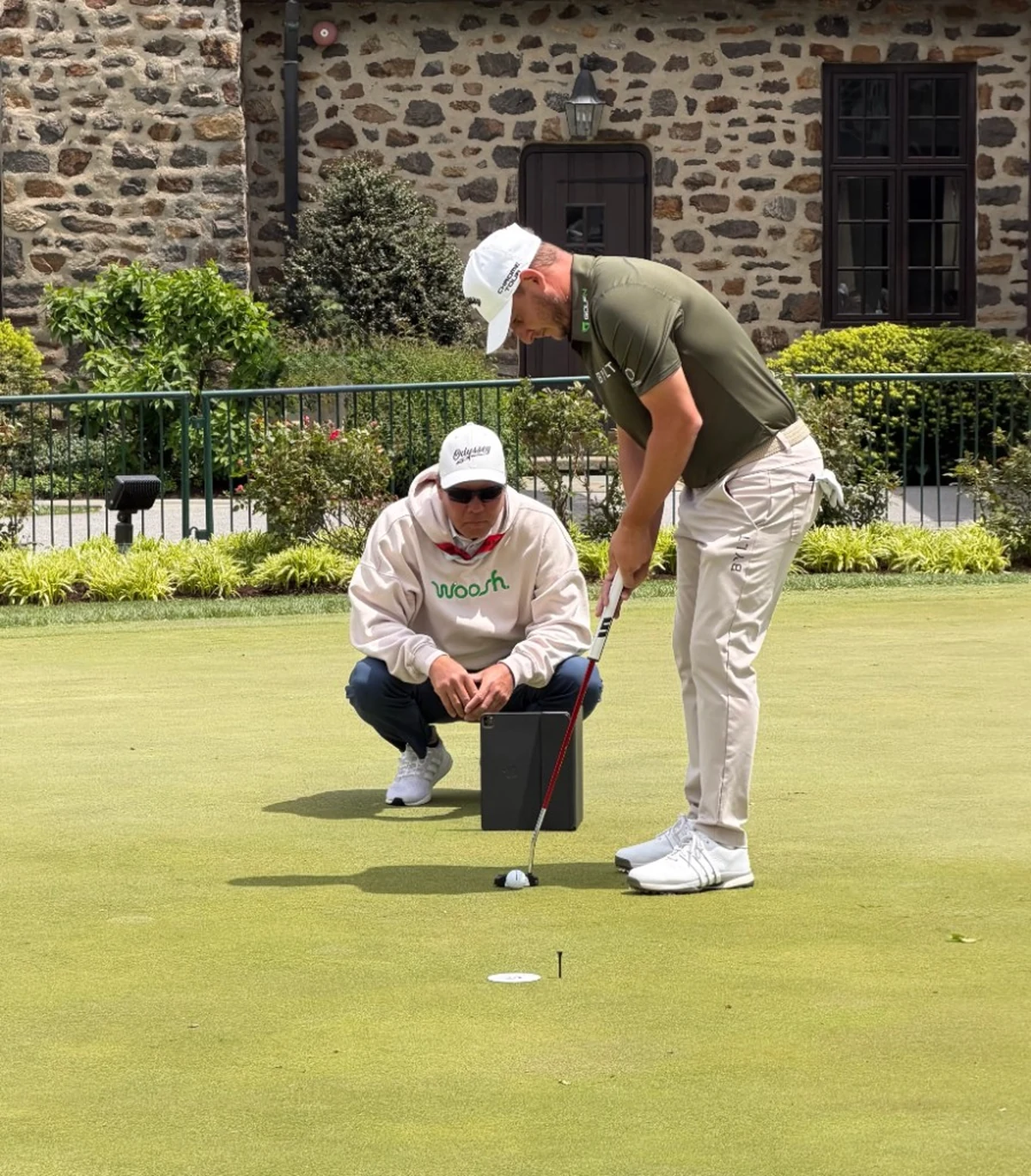PGA Tour coach Derek Uyeda coaching a player on the putting green